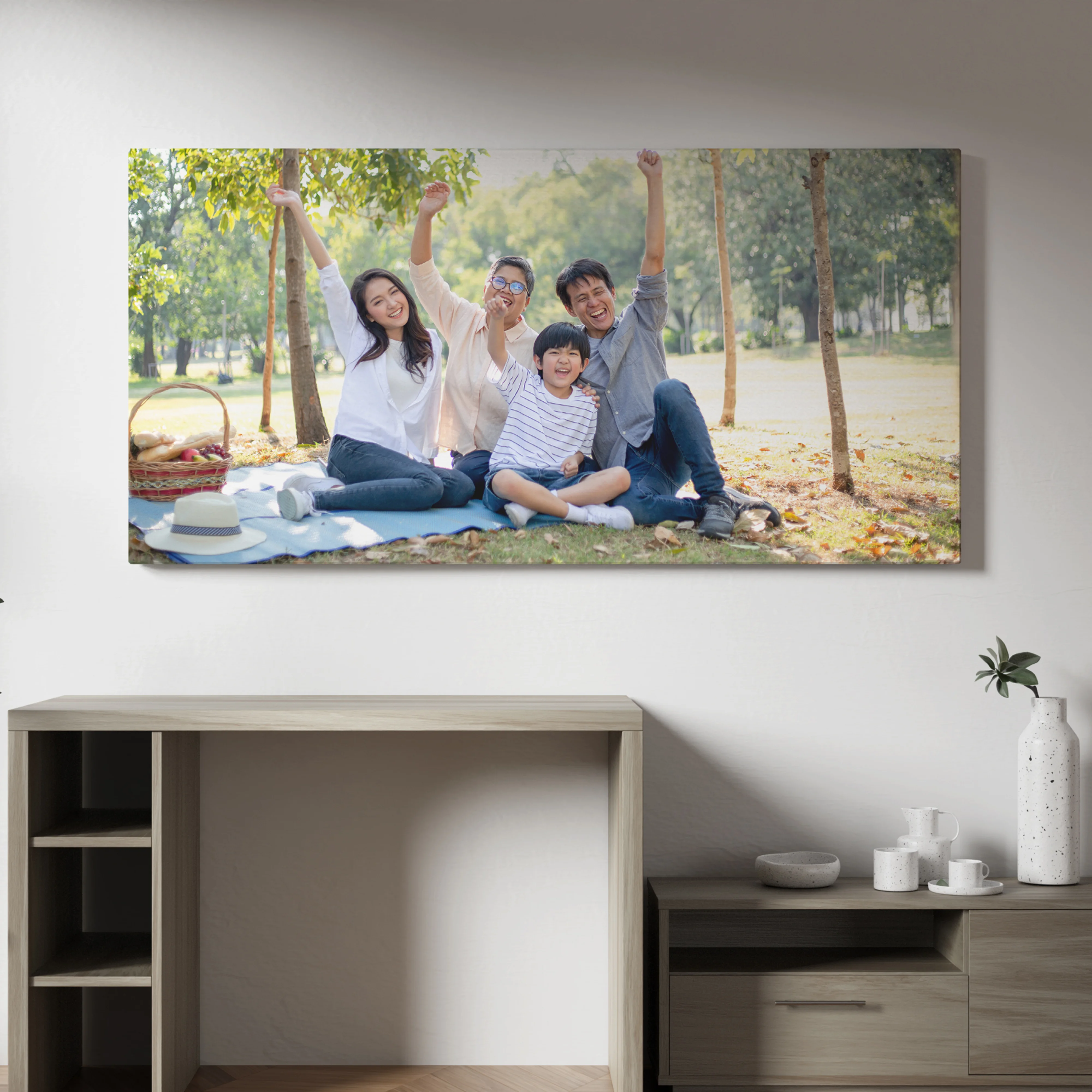 Large wall-mounted photo of a happy family outdoors, arms raised in celebration, hanging above a wooden cabinet in a living room.