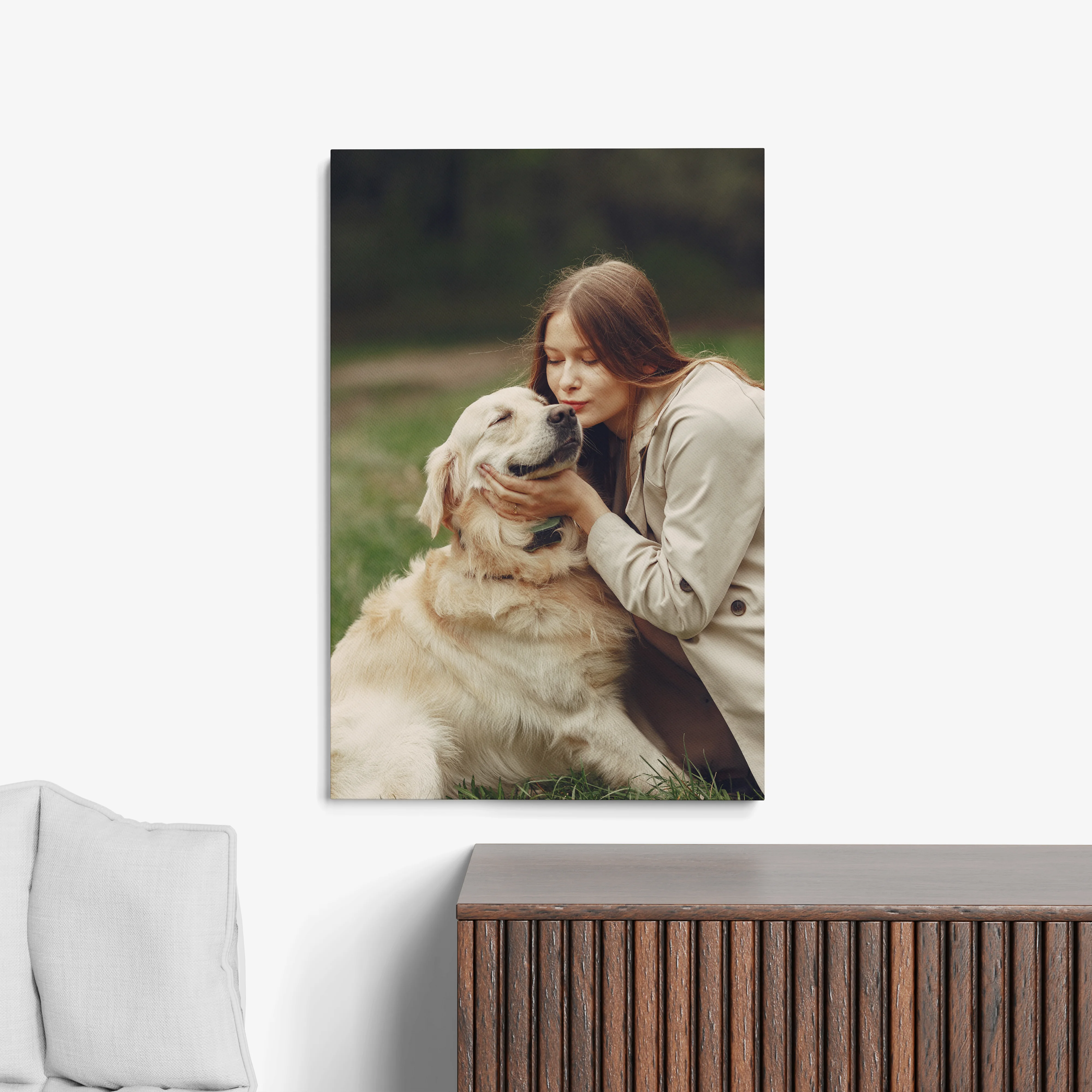 Woman in a beige jacket lovingly hugs a golden retriever outdoors in a park.