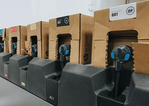 Row of cardboard-wrapped industrial units with blue knobs at a production line in a warehouse